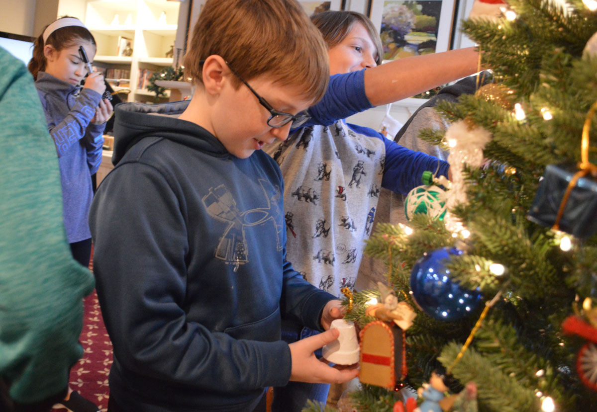 A student places his ornament on the Christmas tree at Beverwyck