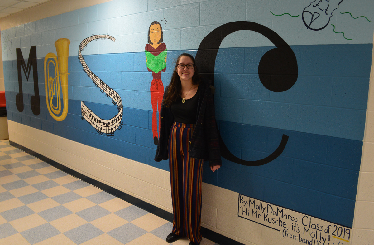 Molly DeMarco in front of the Music mural she painted