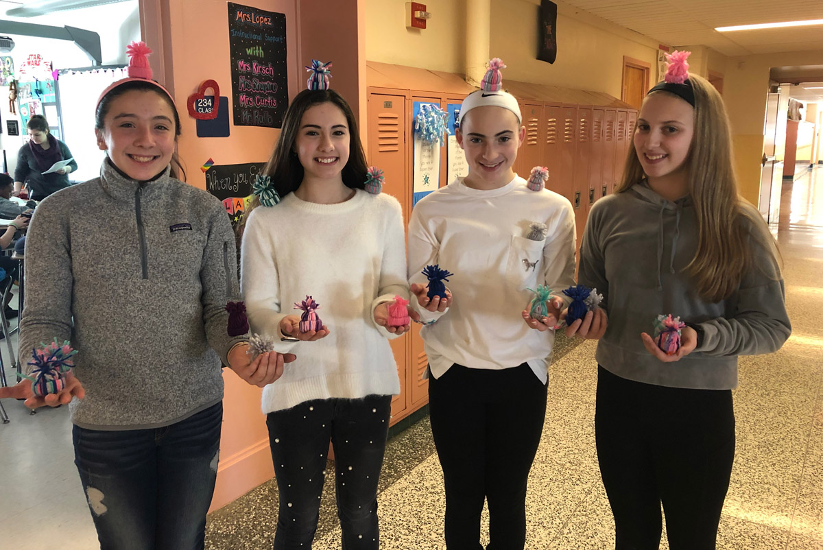 Students hold mini beanies they made
