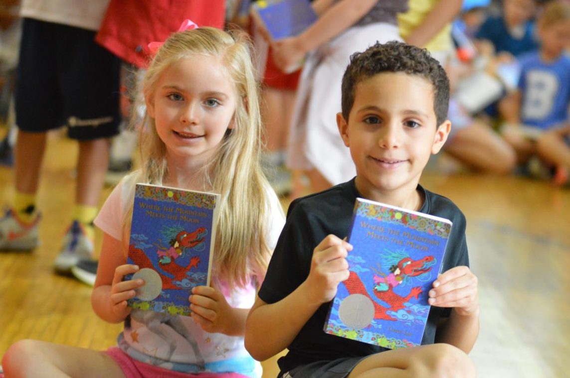 Students hold up books at the Bell Top Book Club assembly