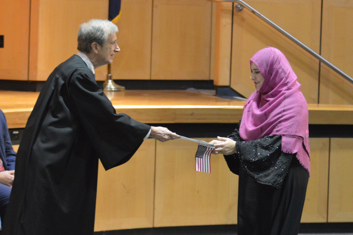 A person receives their U.S. citizenship paperwork at a Naturalization Ceremony at Columbia High School.