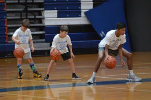 Players dribbling basketballs in the Columbia gym during summer camp