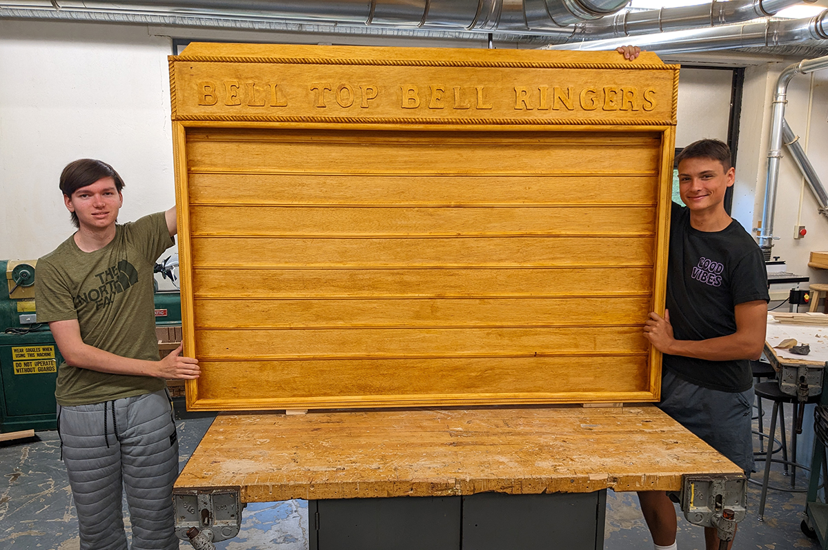 Hunter Whiting '23 and Zackary Alber '23 holding the Bell Top Bell Ringers display case that they built in their Woods II class at Columbia High School.