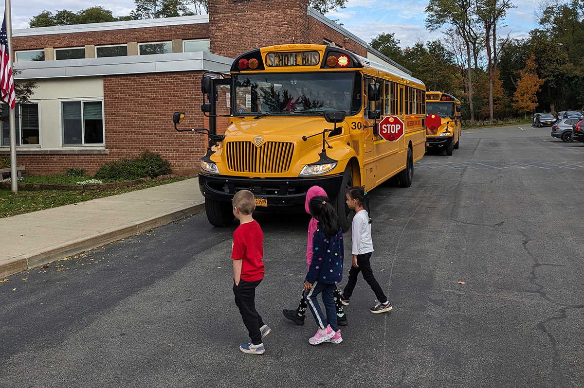 Kindergarten students practice crossing in front of a school bus during a bus safety drill at Red Mill Elementary School.