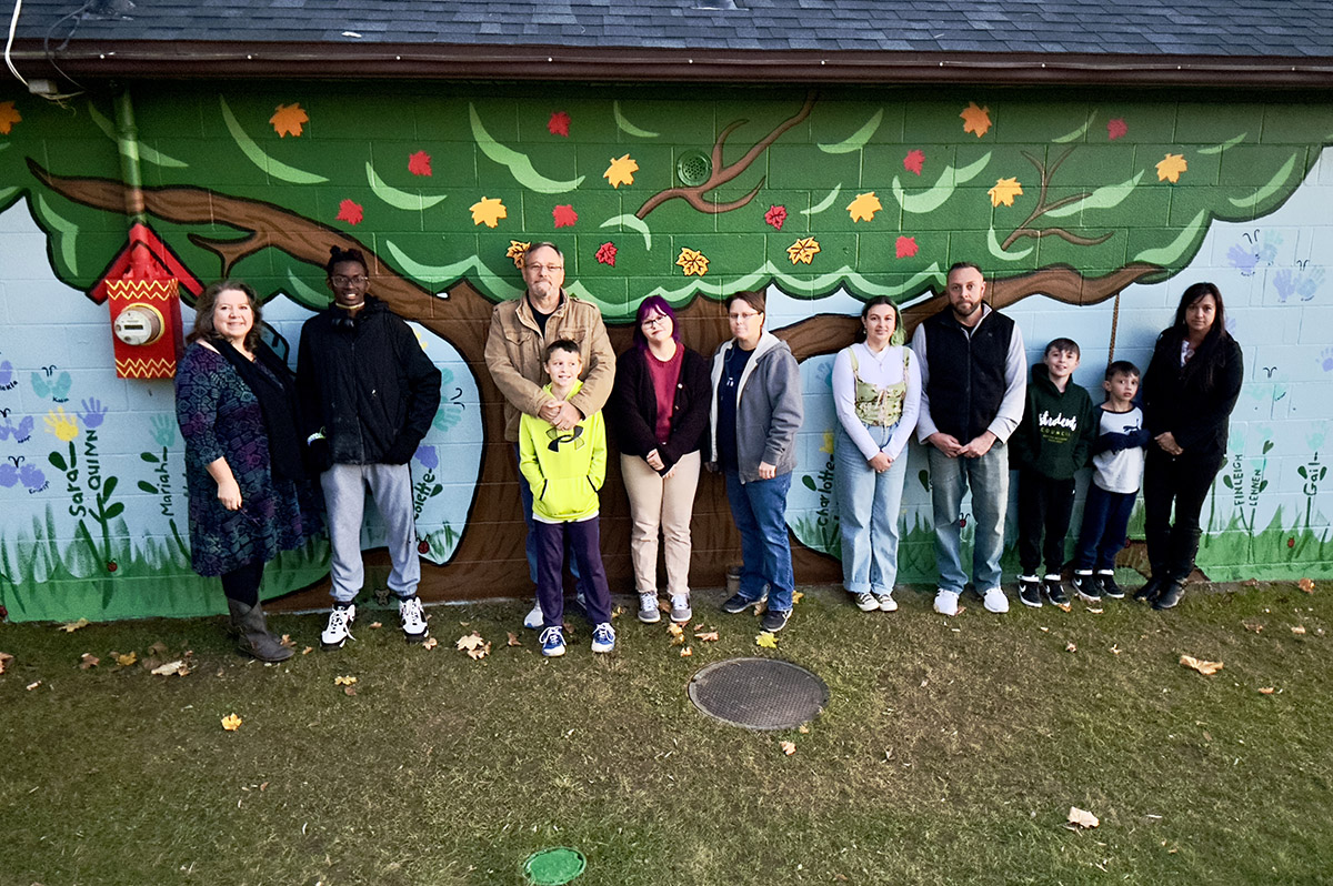 Clover Rodgers '25, Lyla Maguffin '27, and Aries Raphael '24 with Dr. Lisa D'Adamo-Weinstein in front of a mural they created in Hampton Manor Lake Park.