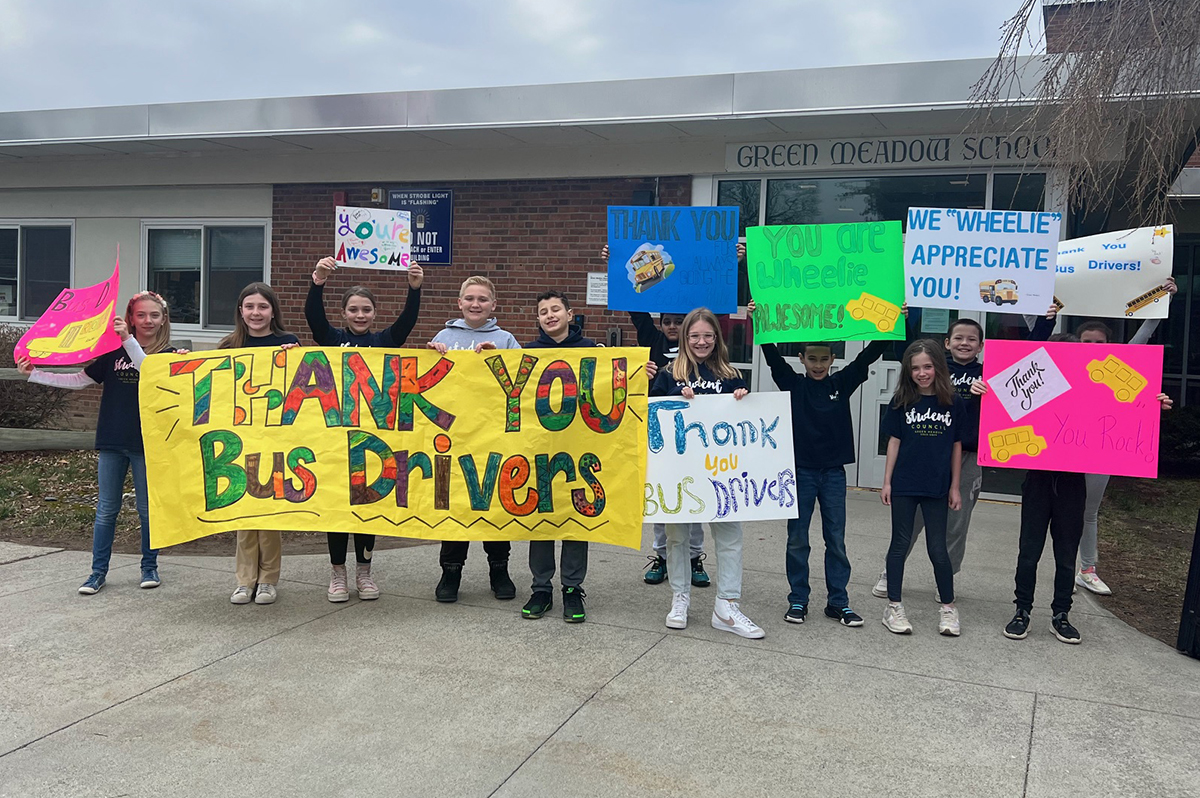 Students holding Bus Driver Appreciation signs
