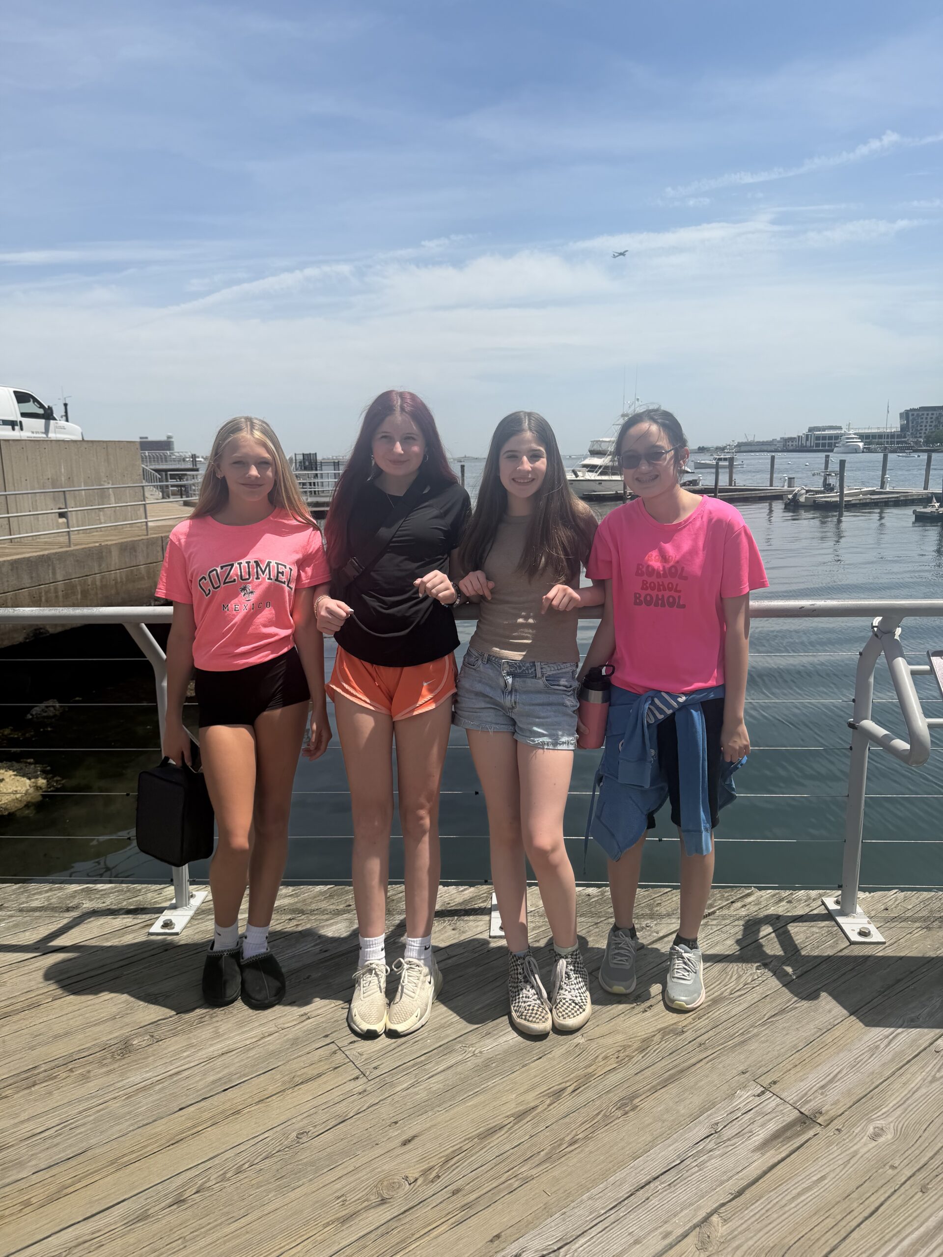 Four students in front of Boston harbor