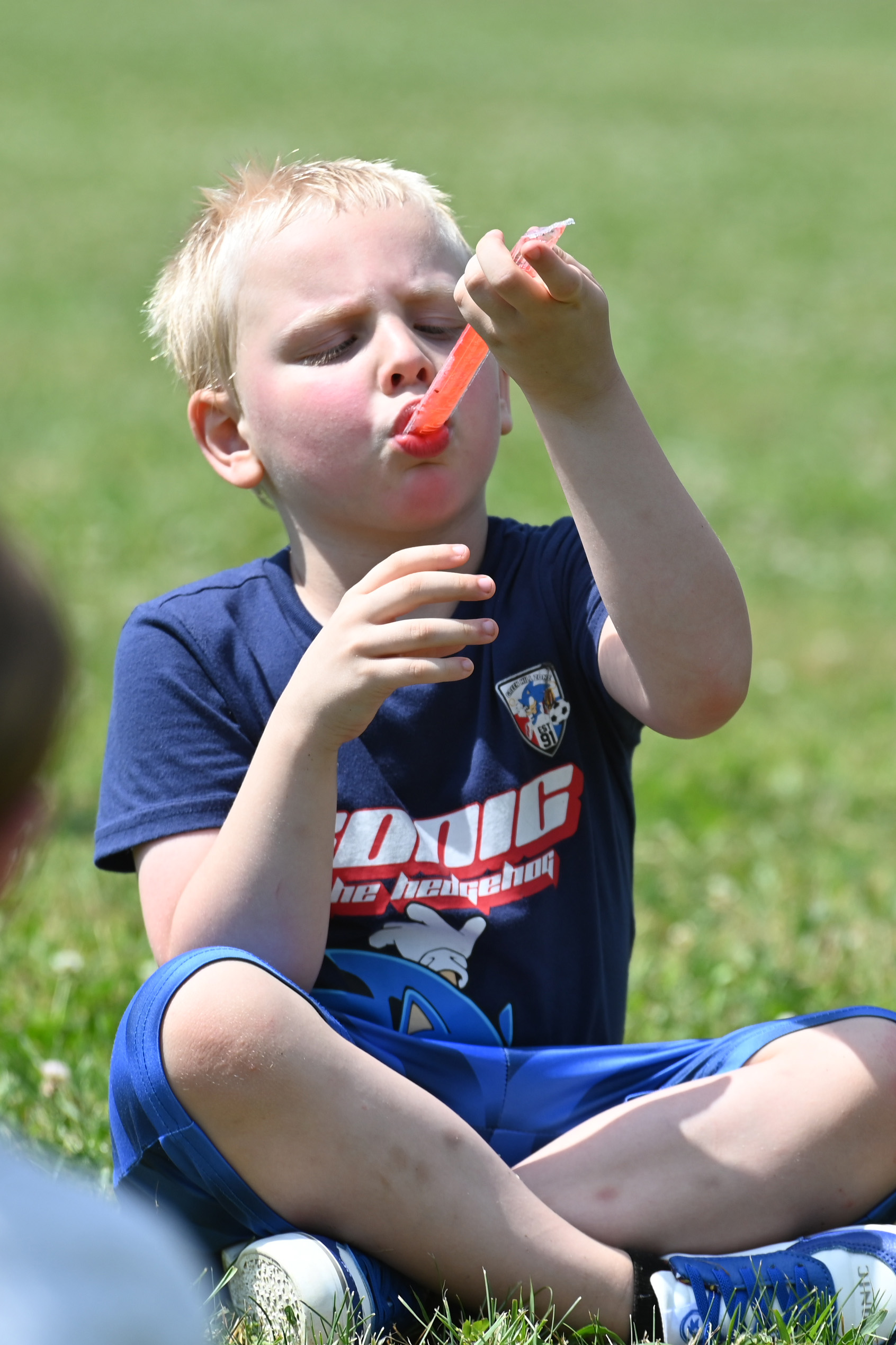 A student eats a red freeze pop at DPS Field Day