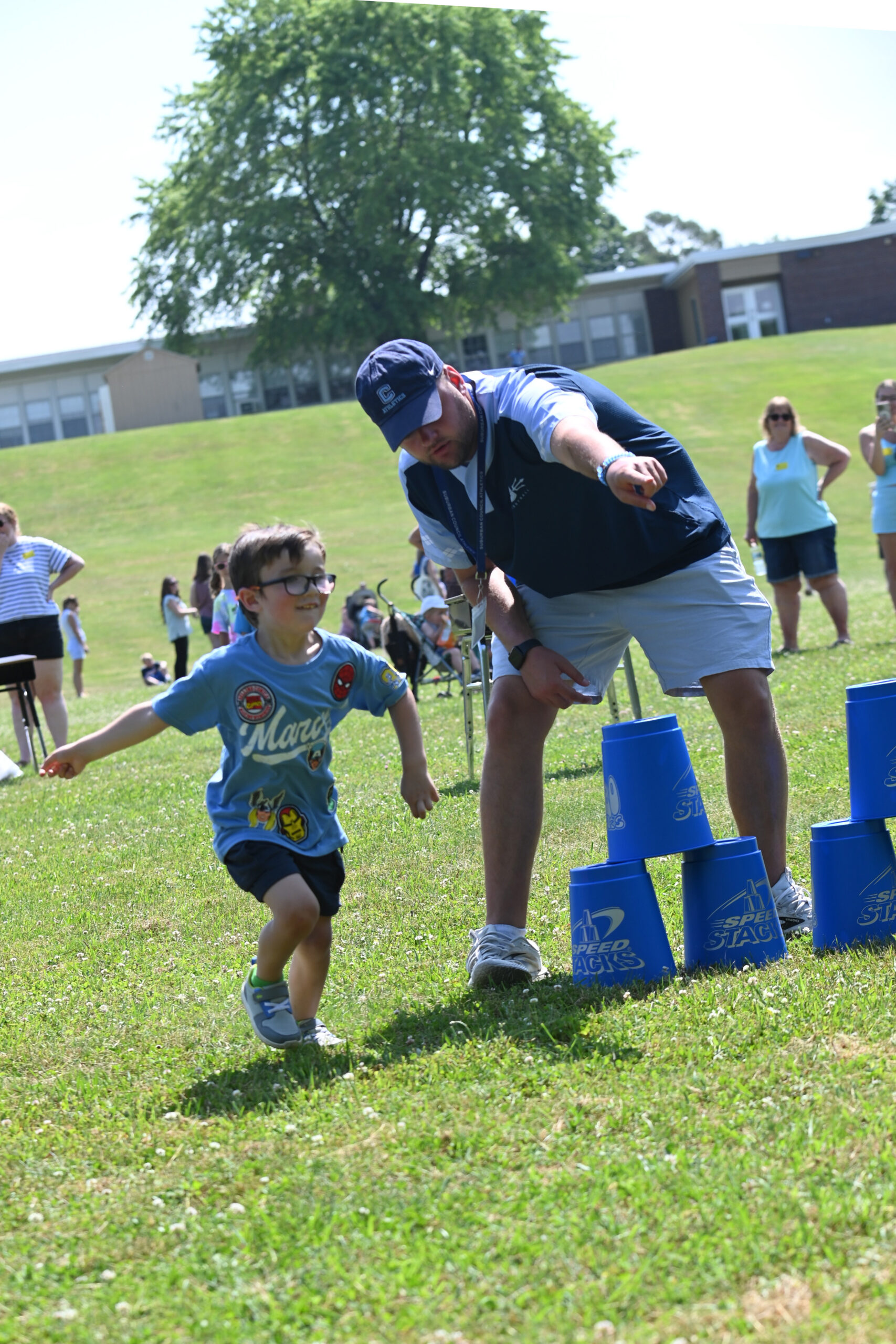 A student runs while being directed by Coach Preston at DPS Field Day