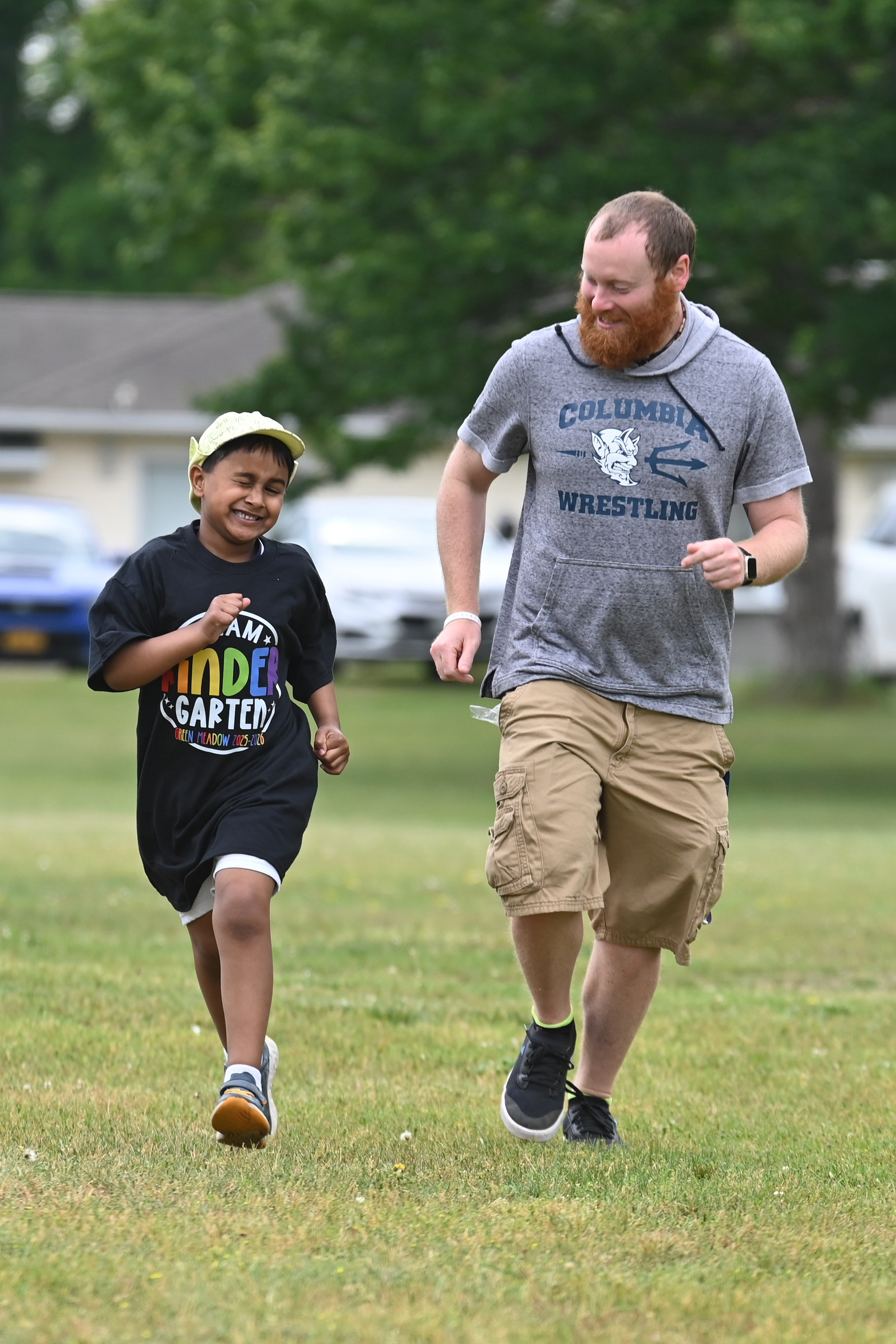 A student running alongside a teaching assistant at Green Meadow Kindergarten Field Day