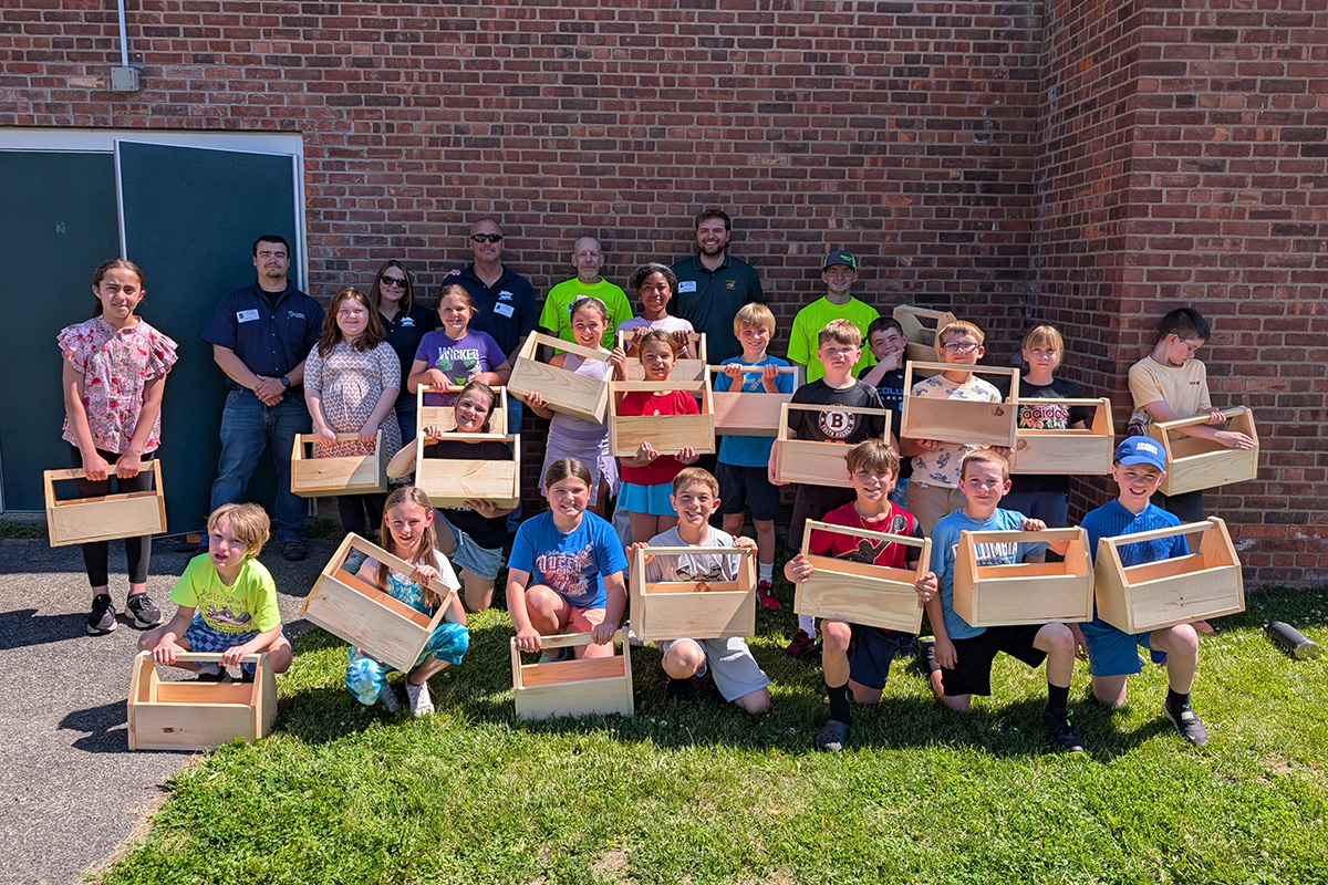 Green Meadow students hold their wooden toolboxes in front of contractors