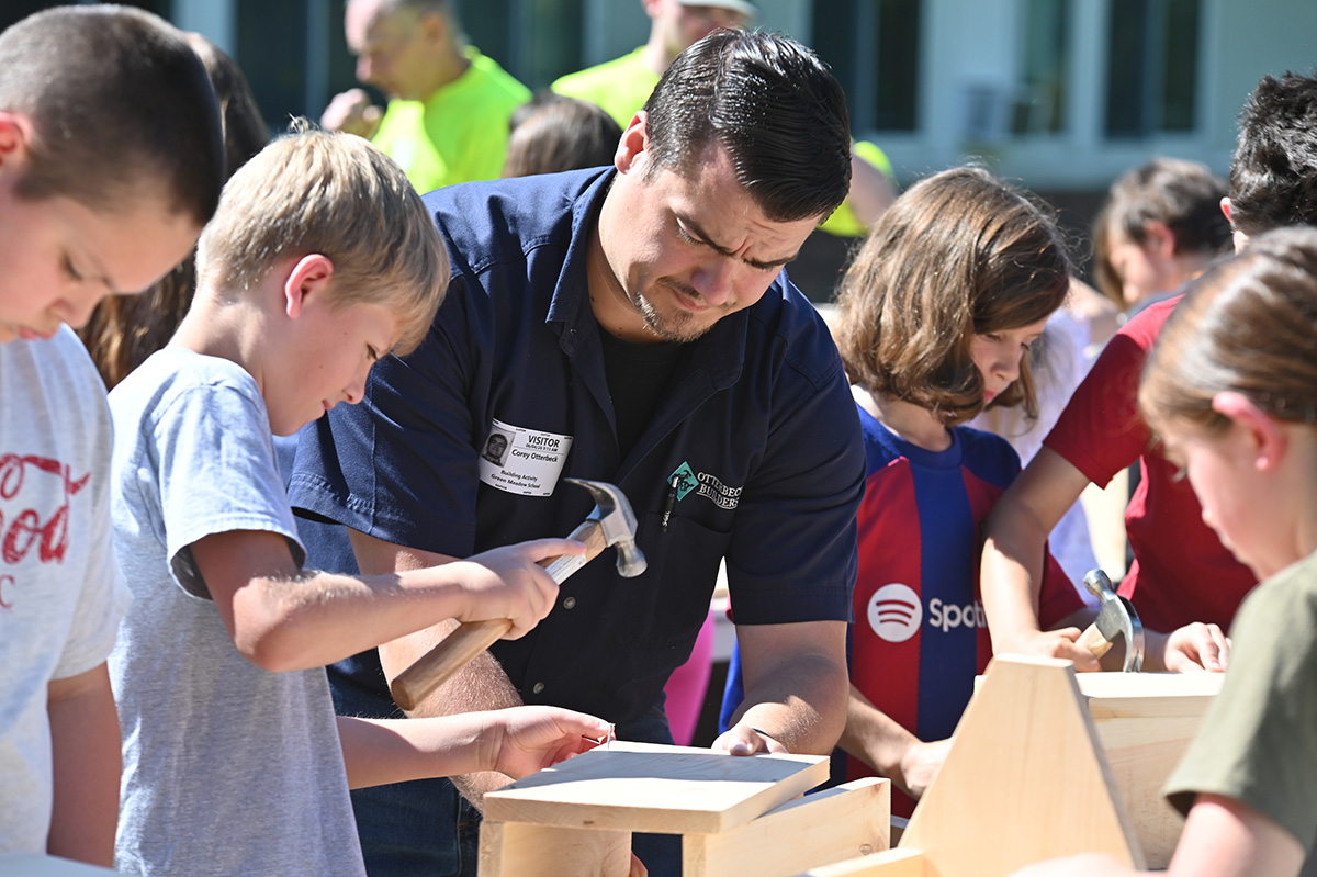 A contractor from Otterbeck Builders helps a student build a wooden toolbox.
